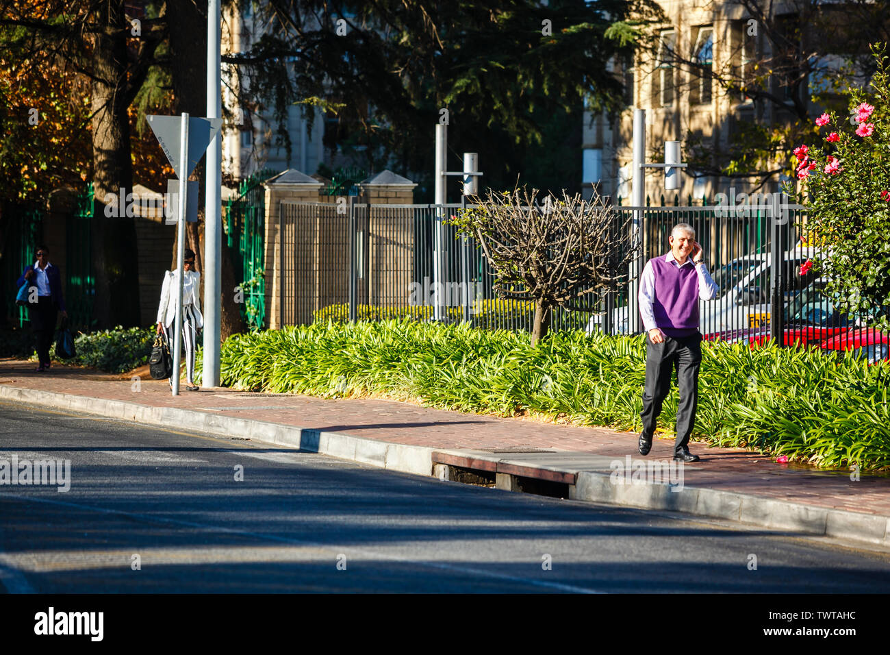 Un homme d'affaires marchant et parlant au téléphone dans le quartier des affaires de Sandton, Johannesburg, Afrique du Sud. Banque D'Images