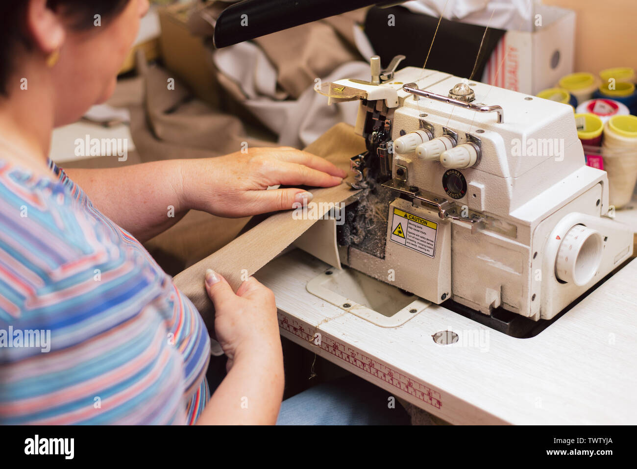 Une vieille femme coud sur une machine à coudre. adapter-surfaces en production. a pris sa retraite engagé passe-temps favori. Banque D'Images