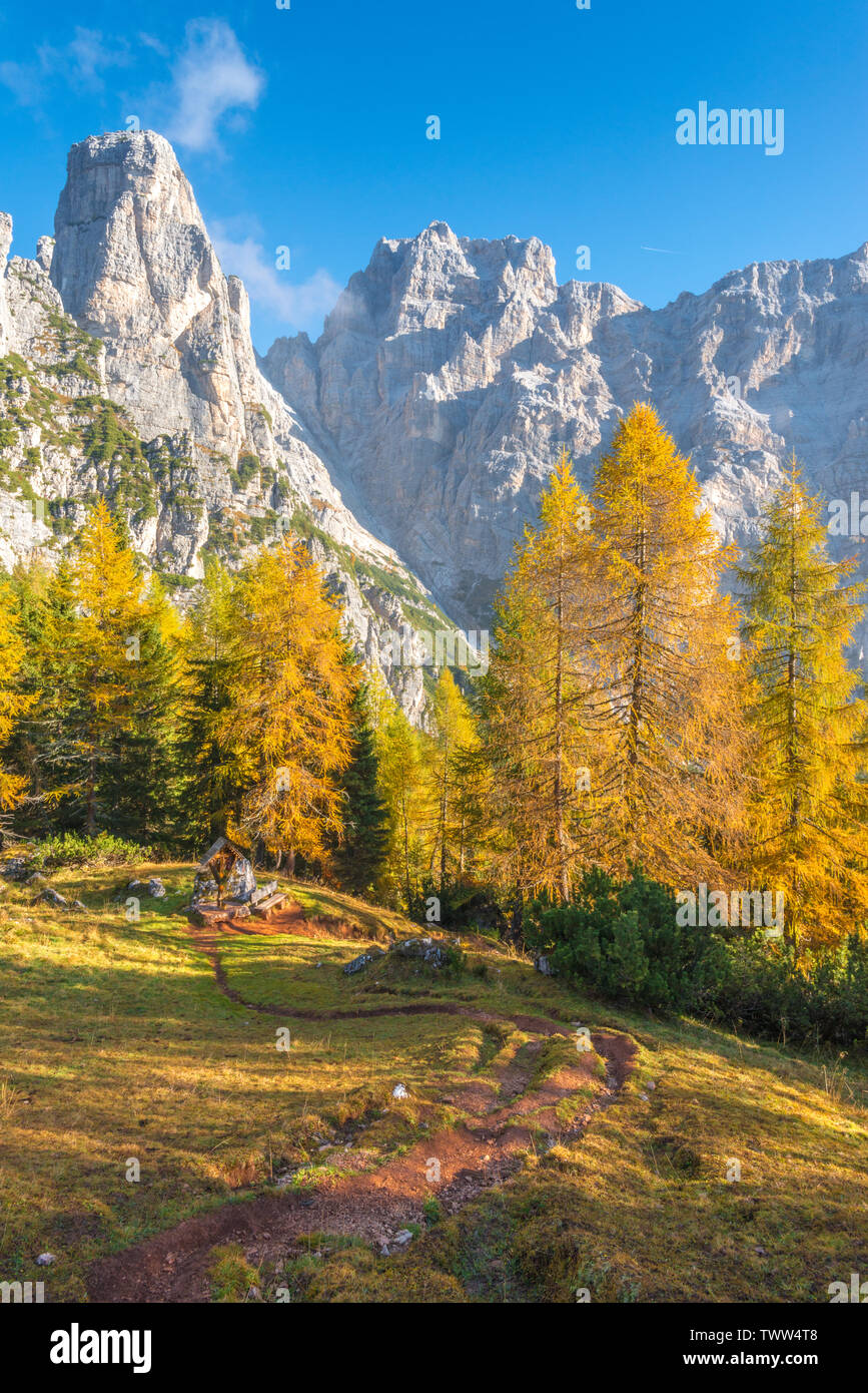 Scène paisible de montagne avec des Alpes italiennes, cross station le long d'un sentier de randonnée et de mélèzes jaune dans la forêt. Feuillage en Italie montagne. Banque D'Images