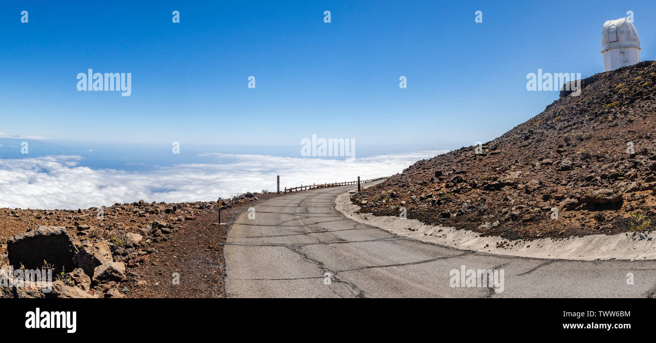 Une haute route courbée au-dessus des nuages, avec un radiotélescope en vue. Cratère de Haleakala, Maui, Hawaii, USA Banque D'Images