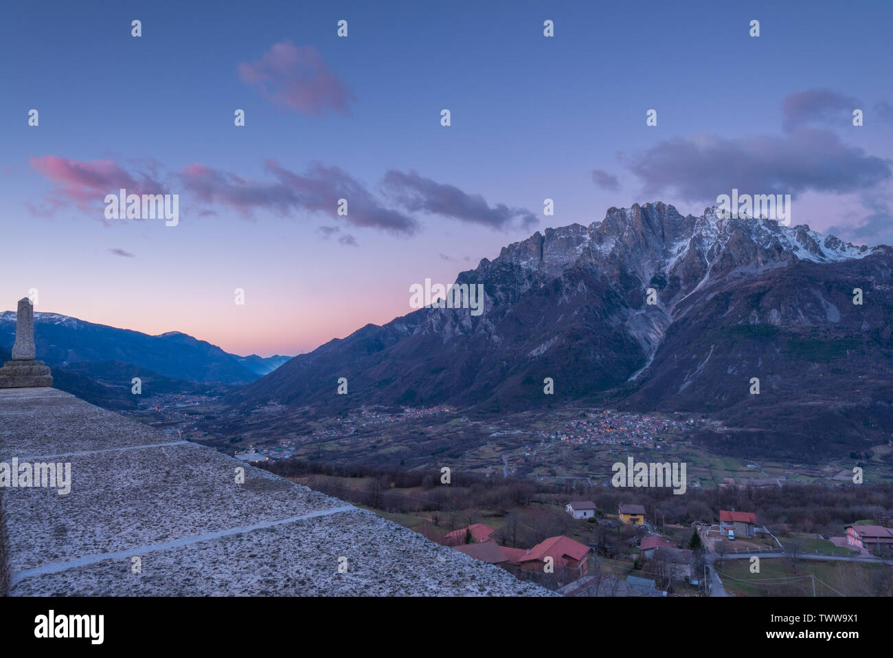 Le lever du soleil sur la ville de Cimbergo en Val Camonica, Italie. Les nuages roses sur les montagnes, les nuages colorés à l'aube dans la vallée. Banque D'Images
