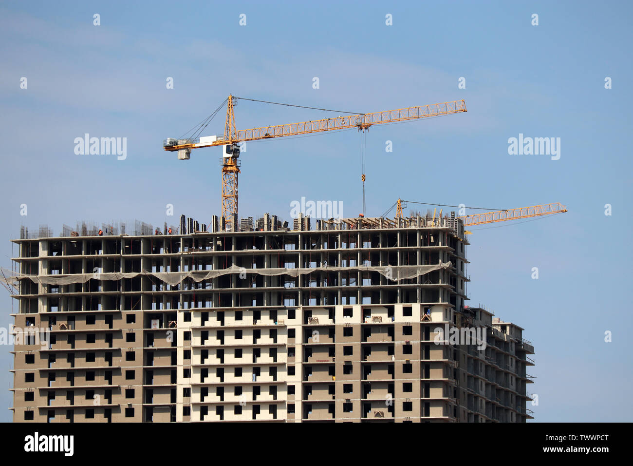 Les grues de construction et bâtiments en construction résidentielle sur fond de ciel bleu avec des nuages blancs Banque D'Images