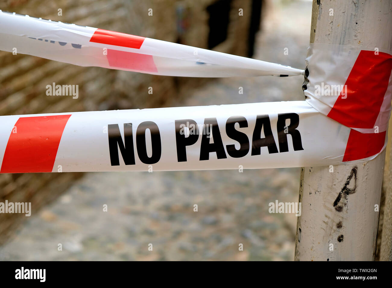 Pas de PASAR (entrée interdite) en espagnol sur le ruban en plastique blanc et rouge pour interdire les voitures / les piétons d'avancer dans une ruelle à Grenade, Espagne. Banque D'Images