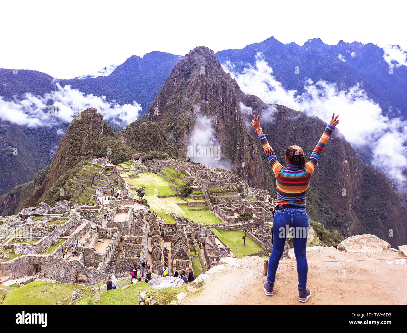 Jeune femme avec bras levés sur fond de Machu Picchu. L'ancienne ville inca, Pérou Banque D'Images