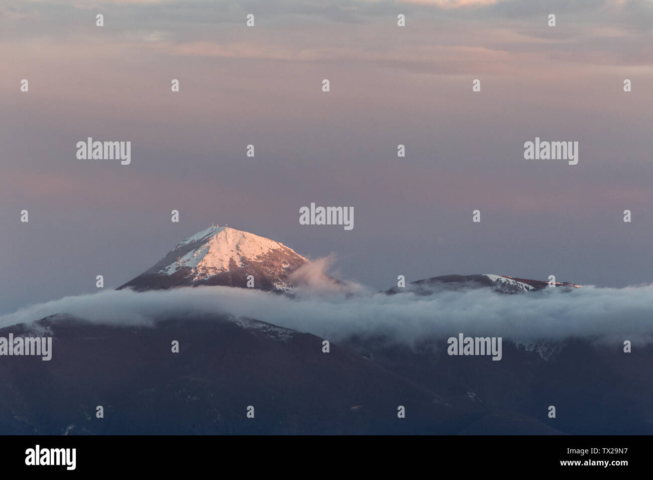 Haut de la montagne couverte de neige au milieu des nuages Banque D'Images