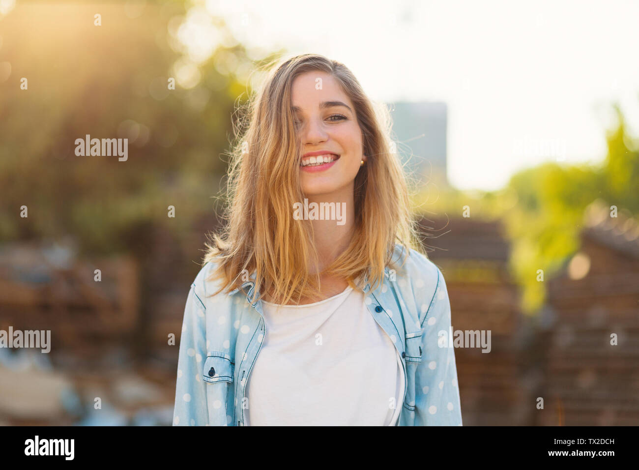 Magnifique Portrait fille avec un beau sourire et de beaux traits de visage sur une journée ensoleillée avec des rayons sur son visage. Douce, romantique, atmosphe Banque D'Images