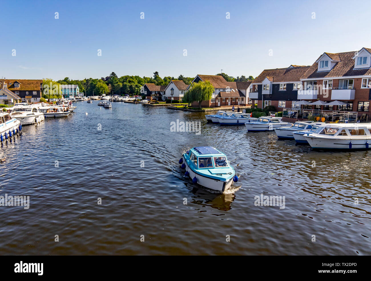 Une vue sur la rivière Bure dans le village de Wroxham montrant non seulement les bateaux de location, location de vacances et hébergement en bord de rivière mais les touristes enjoyi Banque D'Images