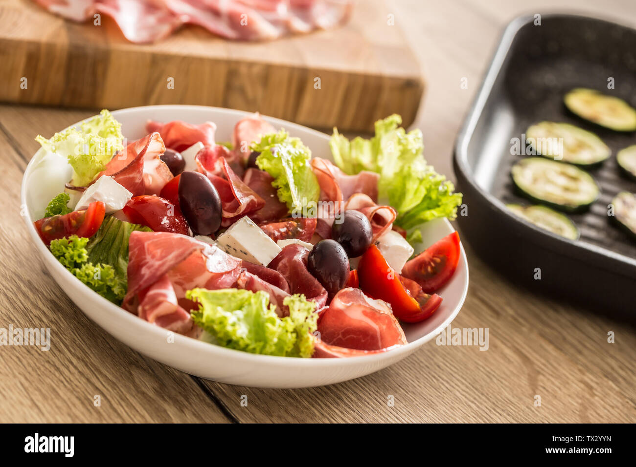 Salade de laitue fraîche avec courgettes grillées coppa di Parma Ham fromage feta tomates olives et huile d'olive Banque D'Images