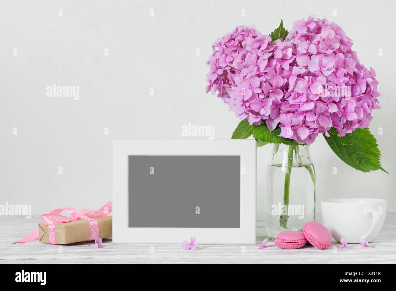 Toujours avec la vie moderne fleurs hortensia rose, cadre photo, tasse à  café et boîte-cadeau sur une table en bois blanc avec copie espace. maison  de vacances ou de mariage backgrou Photo