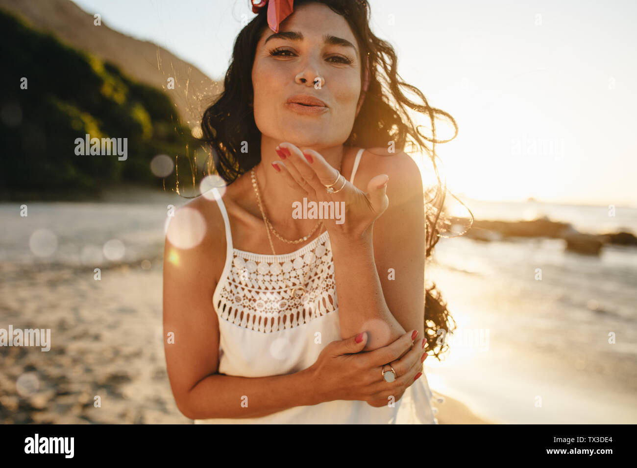 Jolie femme bénéficiant d'une journée d'été sur la plage à souffler un fling baiser à huis clos. Les femmes s'amuser sur ses vacances. Banque D'Images