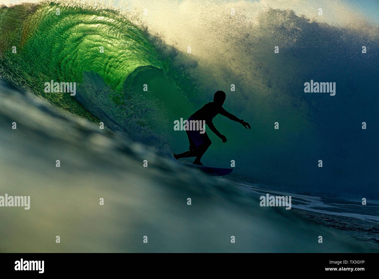 Silhouette homme équitation surfer des vagues d'océan rétroéclairé Banque D'Images