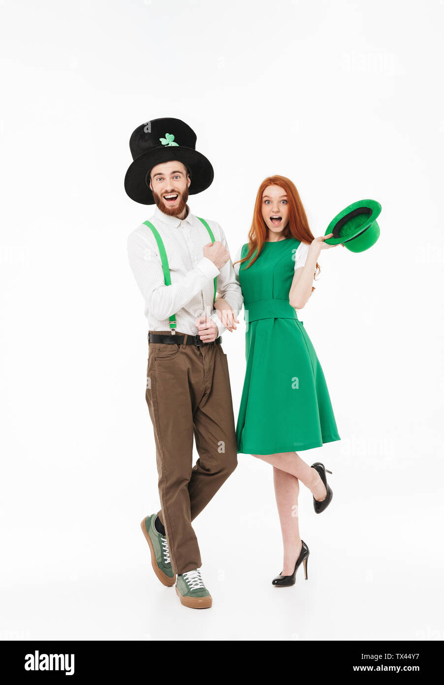 Toute la longueur d'un jeune couple sympathique portant des costumes, la célébration de saint Patrick Day isolated over white background Banque D'Images