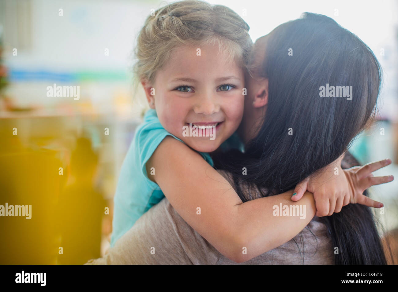 Portrait of smiling girl in kindergarten hugging enseignante préscolaire Banque D'Images