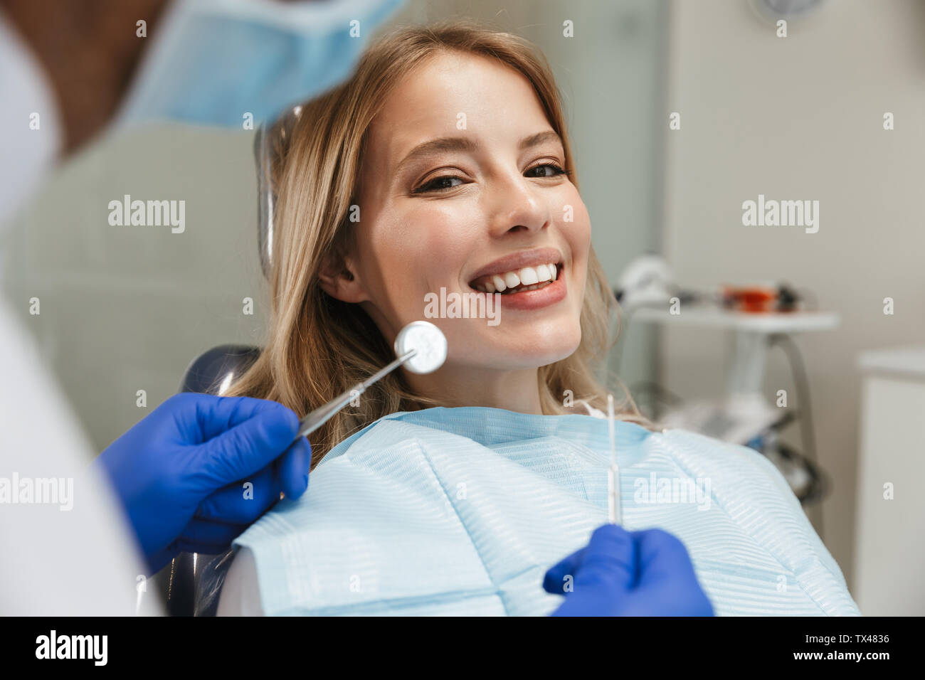 Image de la belle jeune femme assise au fauteuil dentaire au centre médical médecin professionnel tout en fixant ses dents Banque D'Images