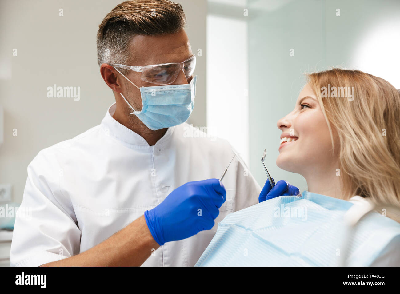 Joyeuse Image de jeune femme assise au fauteuil dentaire au centre médical médecin professionnel tout en fixant ses dents Banque D'Images