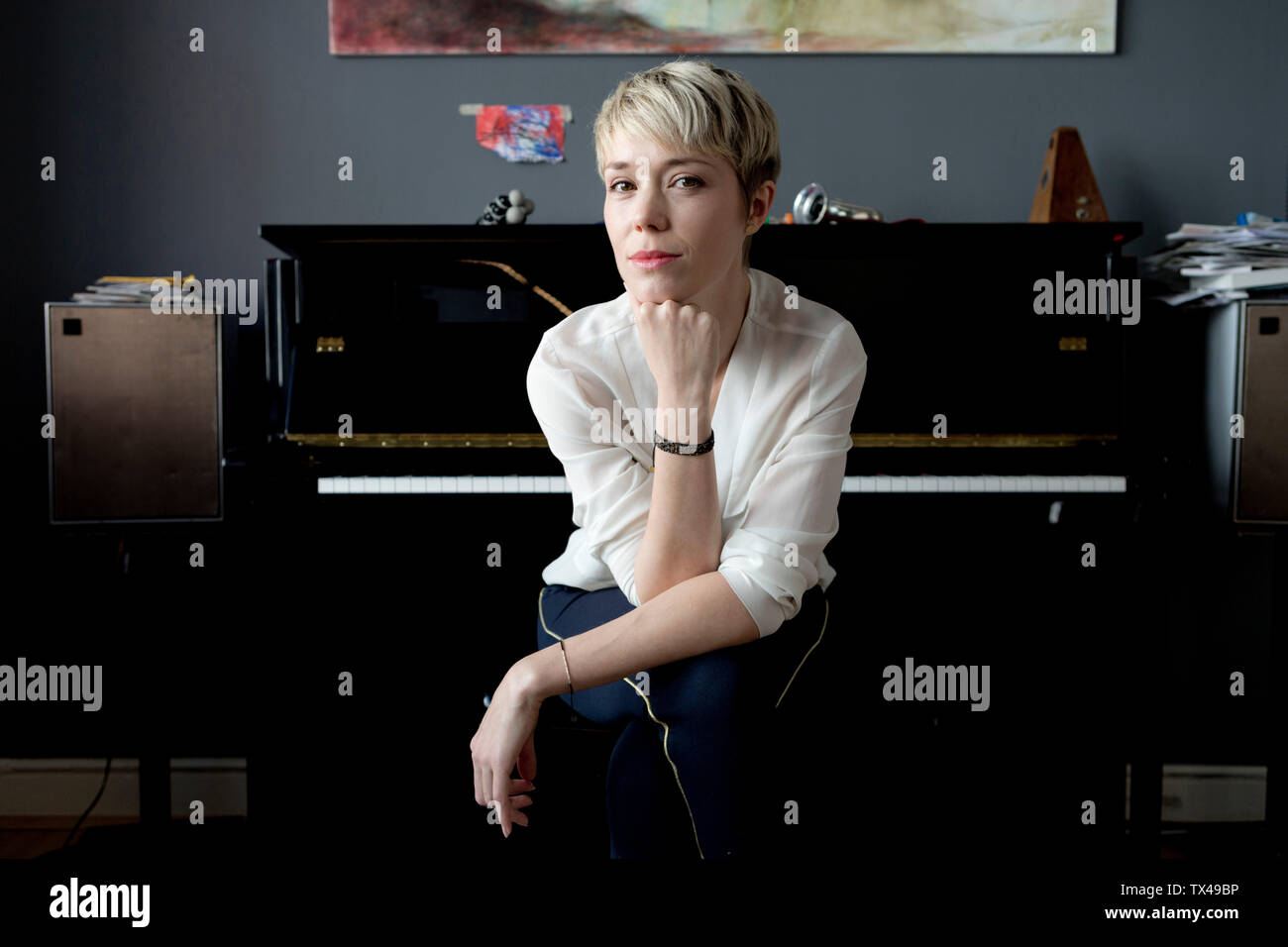 Portrait de femme blonde assise dans sa salle de musique en face de piano Banque D'Images