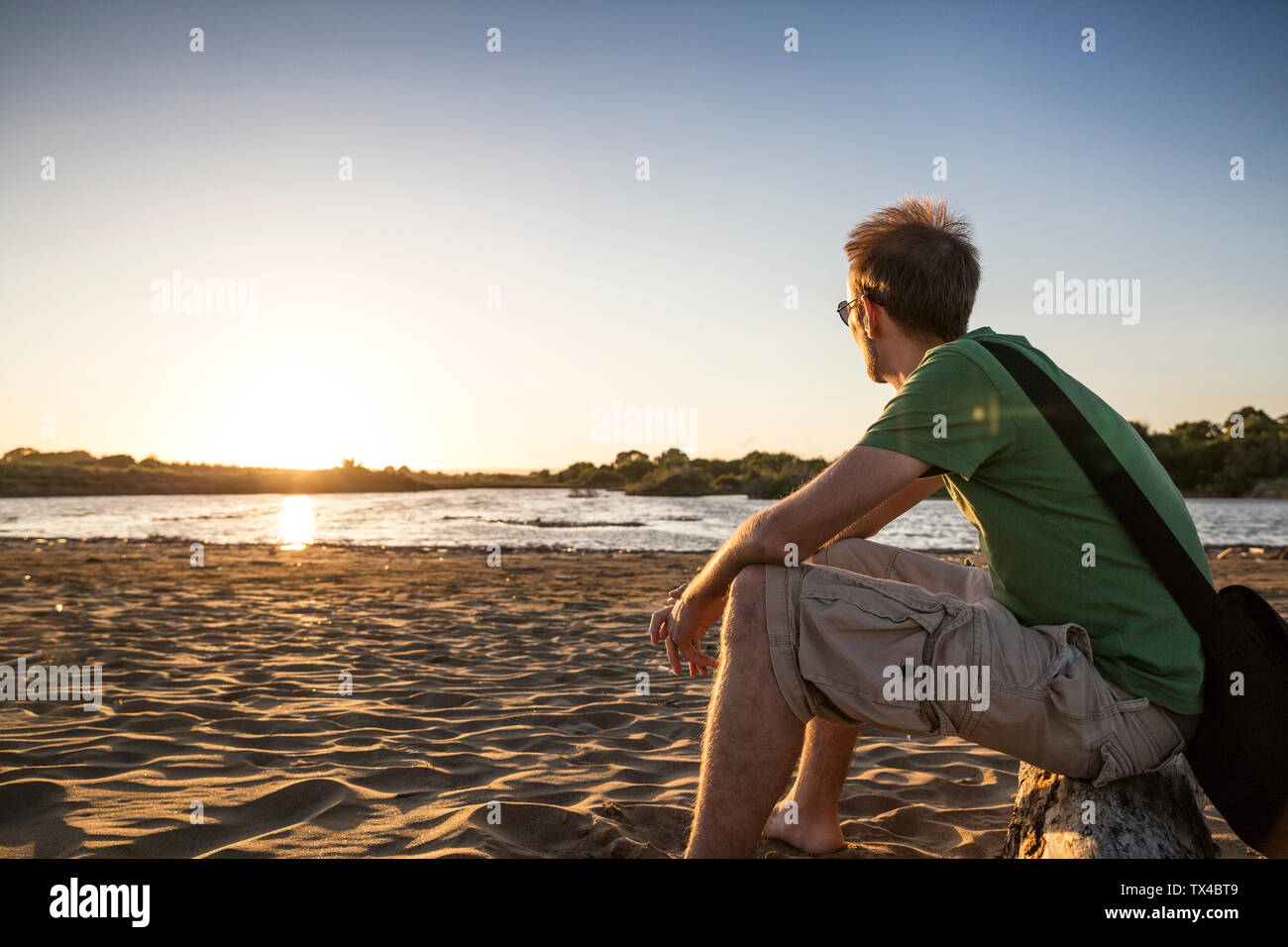 Italie, Sicile, jeune homme enyoing le coucher du soleil à la plage de Eloro Banque D'Images