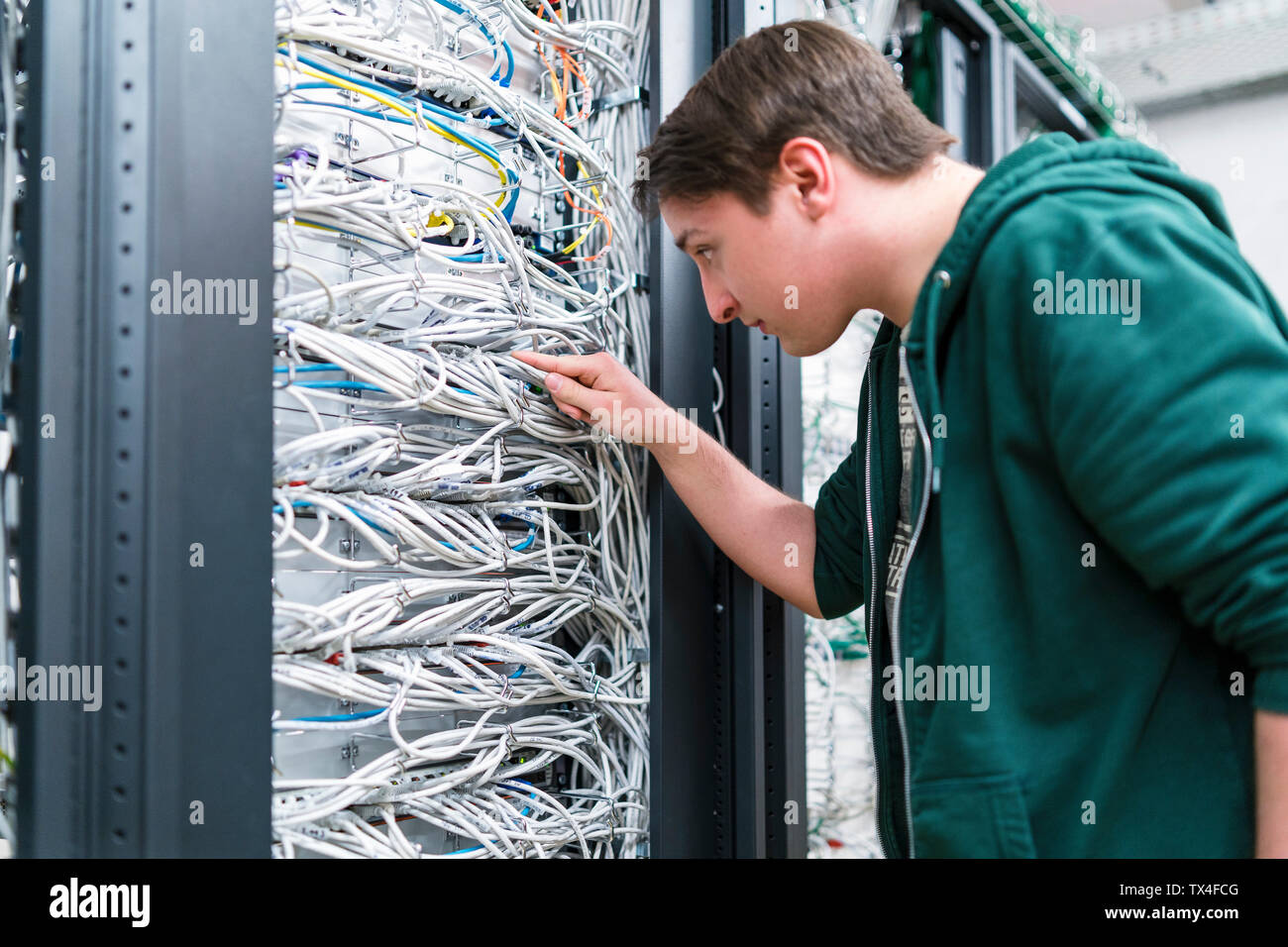 Adolescent travaillant avec les câbles dans la salle serveur Banque D'Images