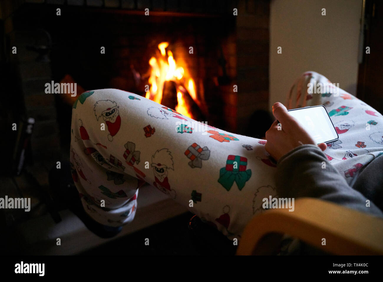 Homme assis devant le foyer, 5 pantalons de Noël à l'aide de mobile phone Banque D'Images