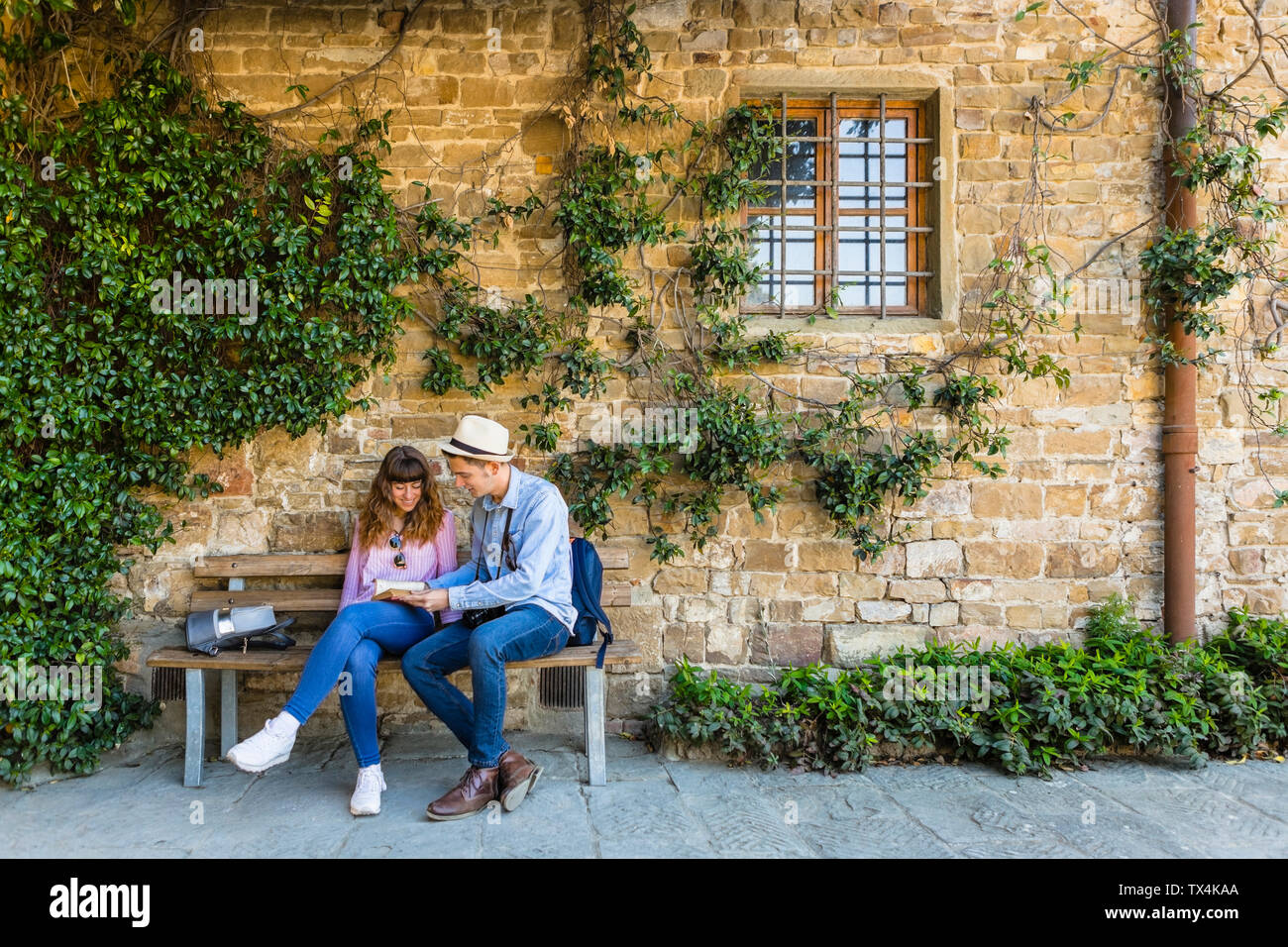 Jeune couple sur un séjour en ville, assis sur un banc, prenant une pause Banque D'Images
