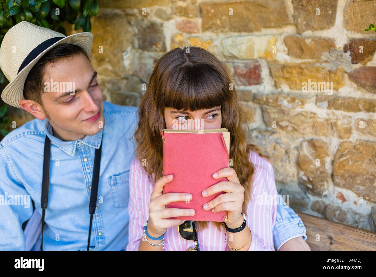 Jeune couple sur un séjour en ville, assis sur un banc, guide de lecture Banque D'Images