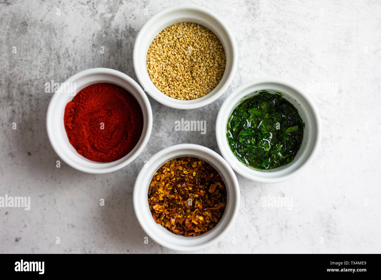 Paprika en poudre, piment, sésame et le persil avec l'huile dans des bols Banque D'Images