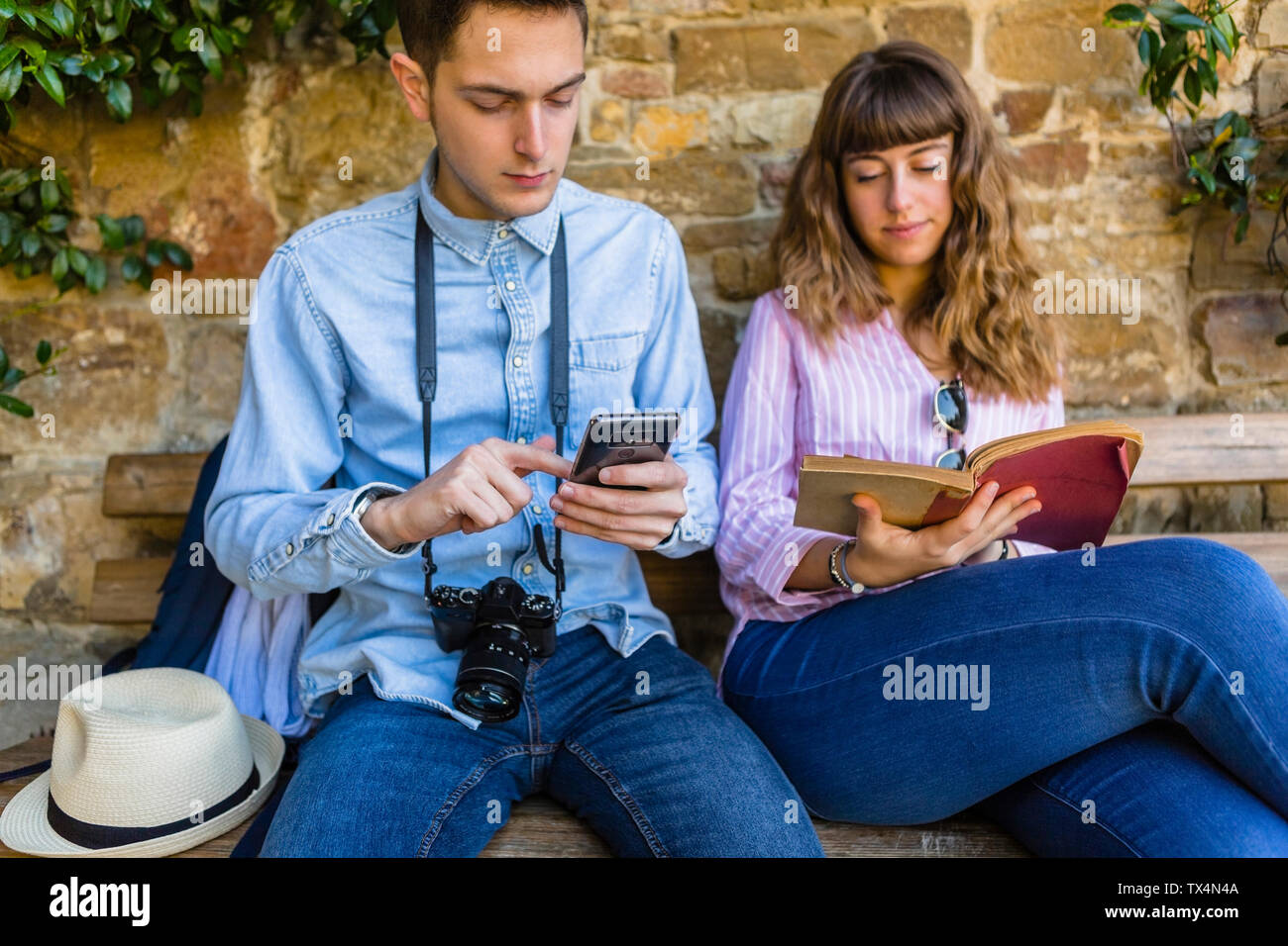 Jeune couple sur un séjour en ville, assis sur un banc, guide de lecture Banque D'Images