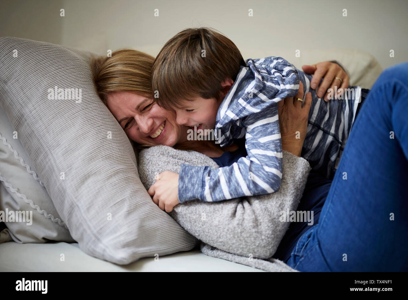 La mère et le fils de câlins sur le canapé Banque D'Images