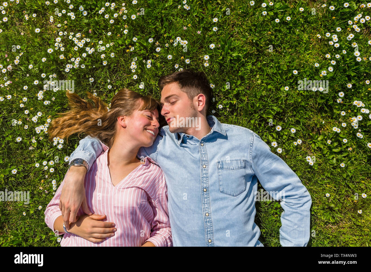 Happy young couple relaxing on grass in a park, overhead view Banque D'Images