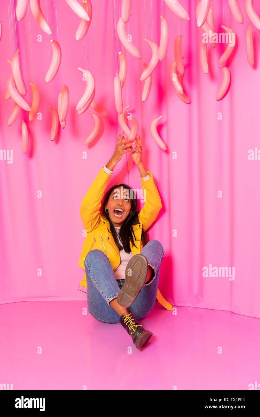 Jeune femme criant à un parc à thème couvert avec ballants bananes rose Banque D'Images