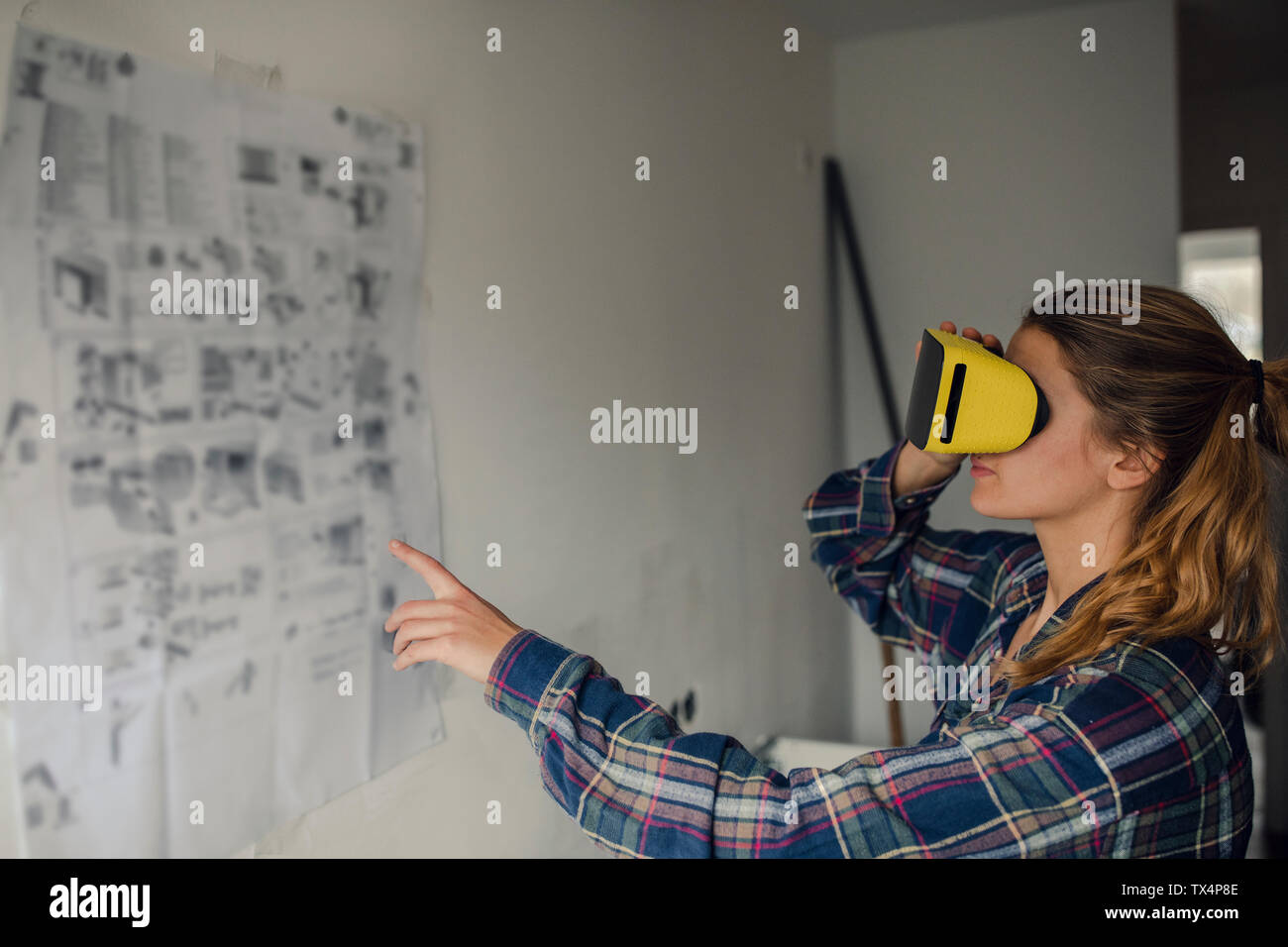 Jeune femme portant des lunettes VR avec des instructions de montage au mur Banque D'Images