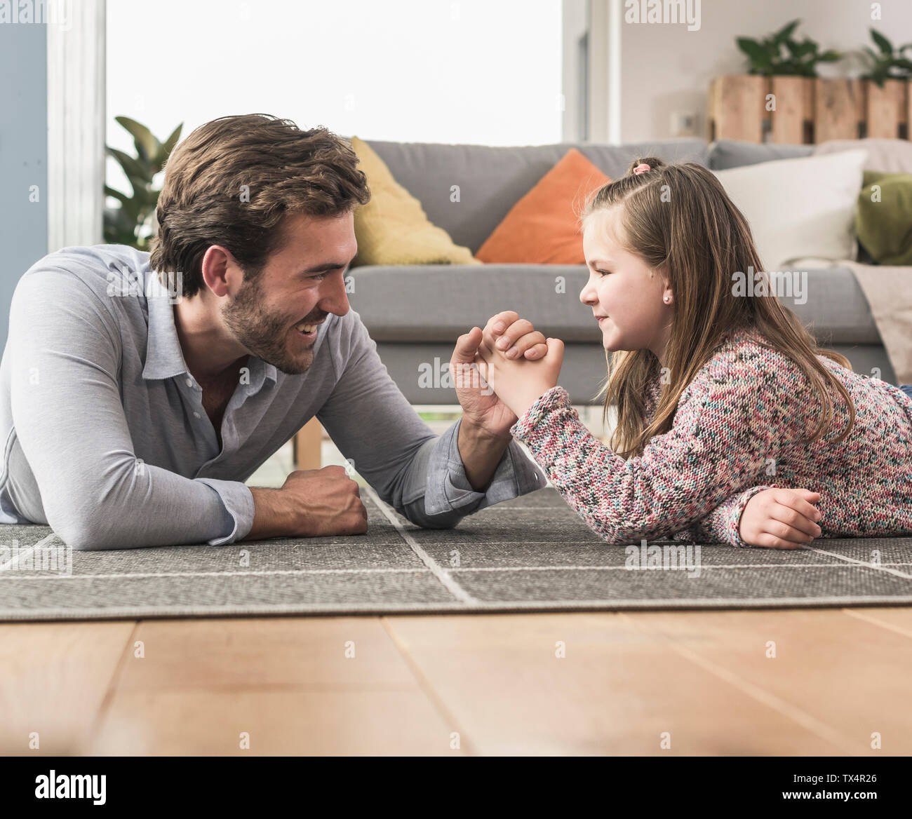 Jeune homme et petite fille étendue sur le sol, bras de fer Banque D'Images