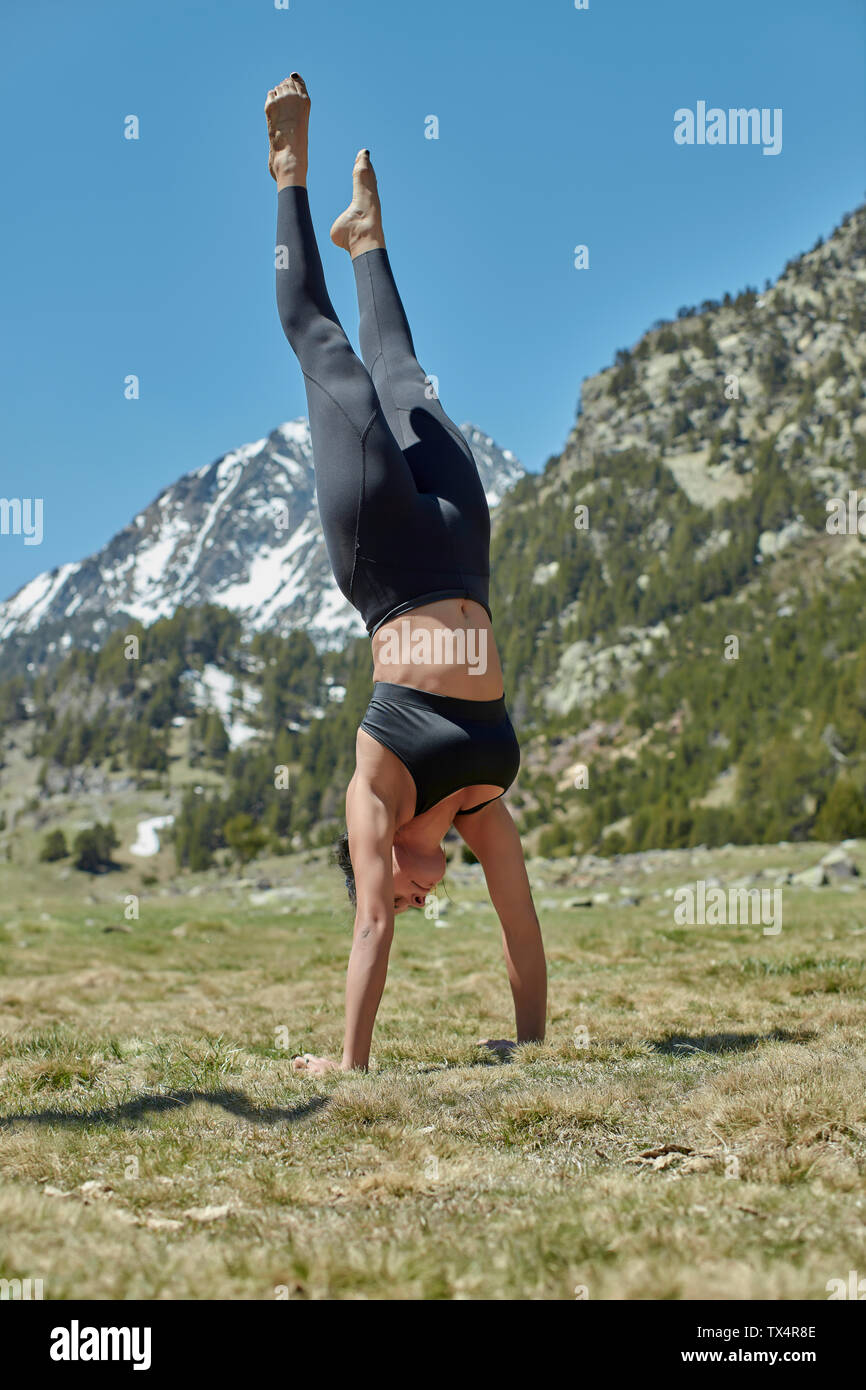 Young woman doing yoga dans la nature, handstand on meadow Banque D'Images