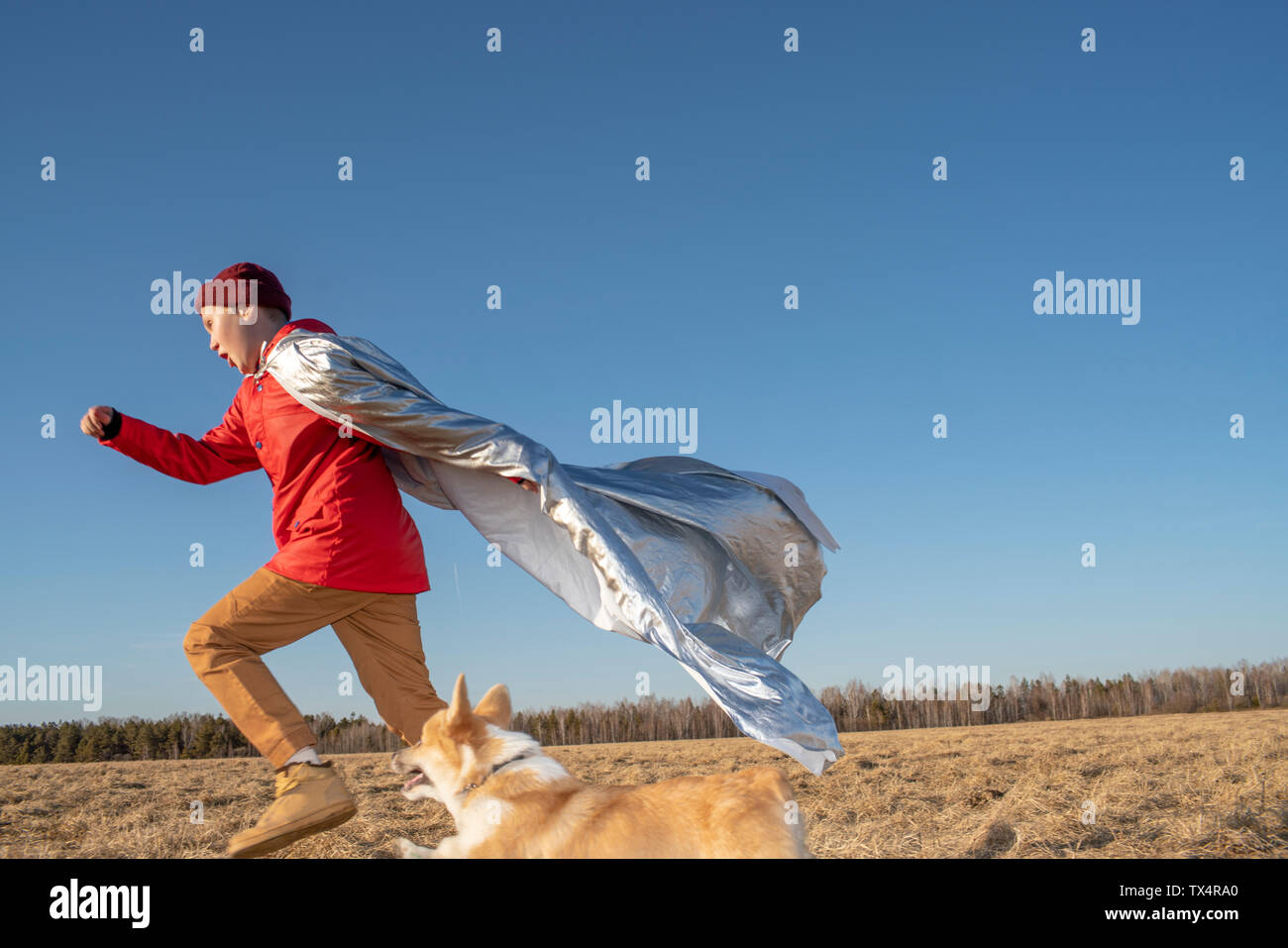 Garçon habillé en super héros courir avec le chien dans un paysage de steppe Banque D'Images