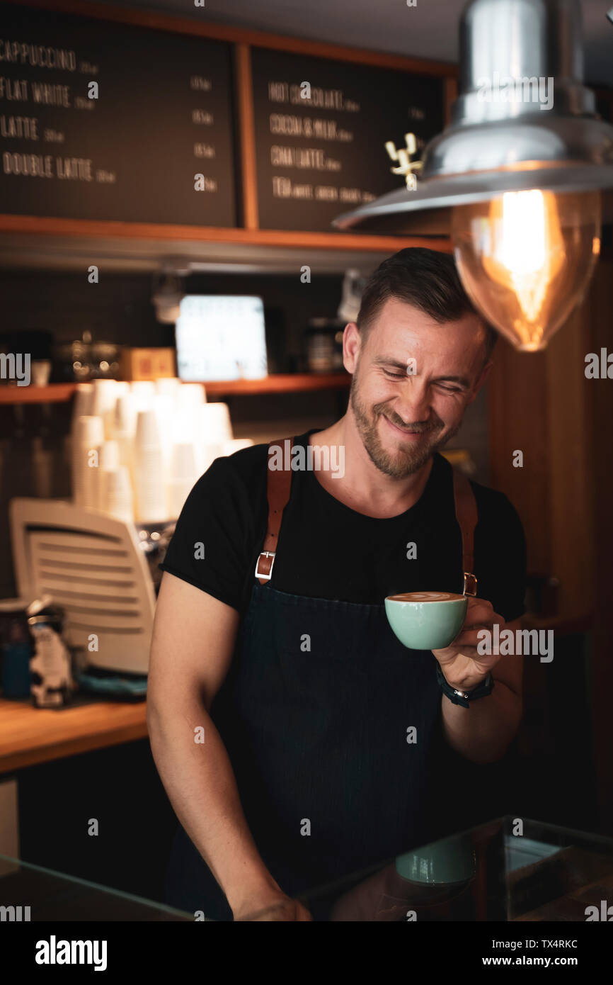 Smiling barista tenant une tasse de café au coffee shop Banque D'Images