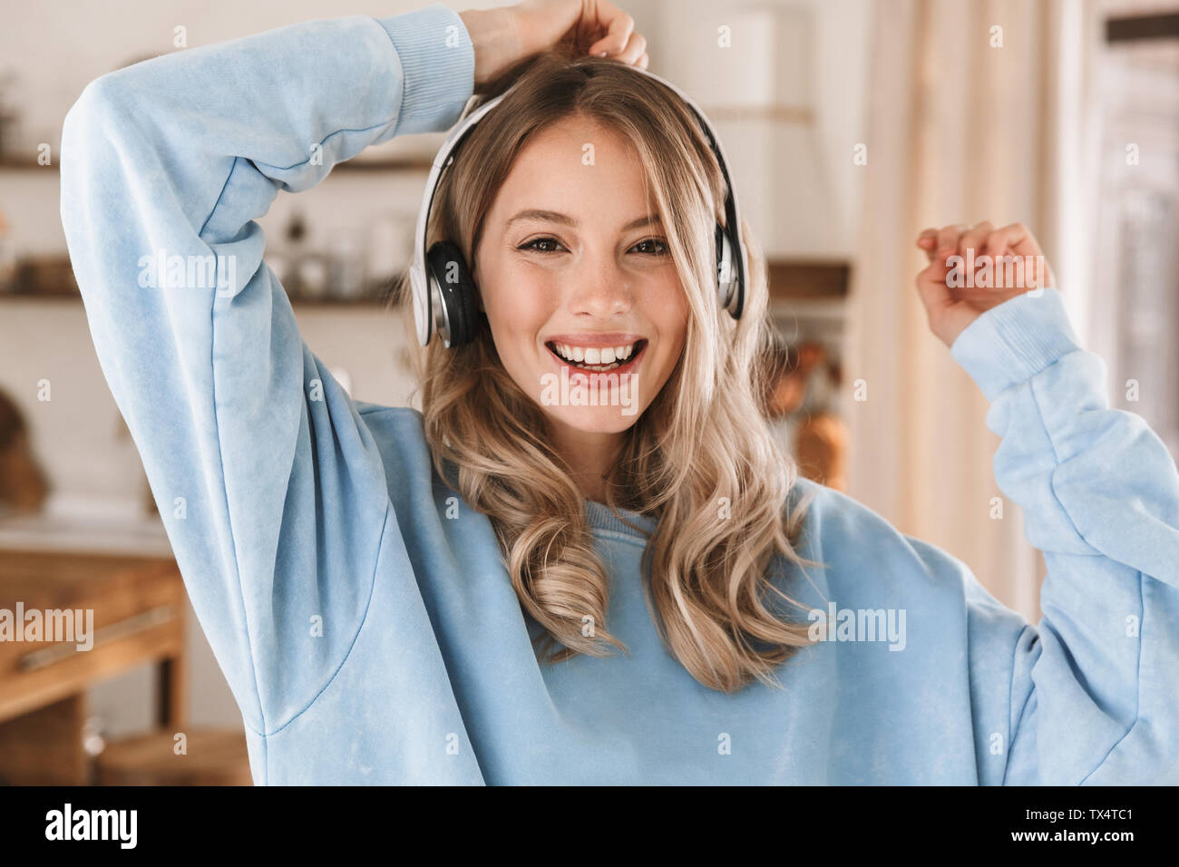 Portrait of gorgeous blonde girl 20s portant des écouteurs de sourire et de joie tout en écoutant de la musique à la maison Banque D'Images