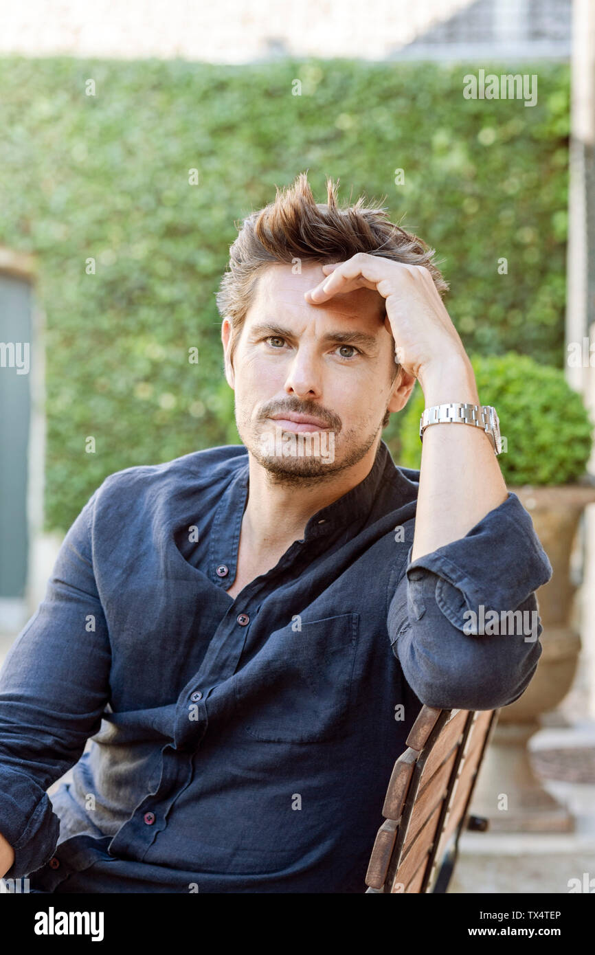 Mid adult man sitting dans son jardin luxuriant Banque D'Images