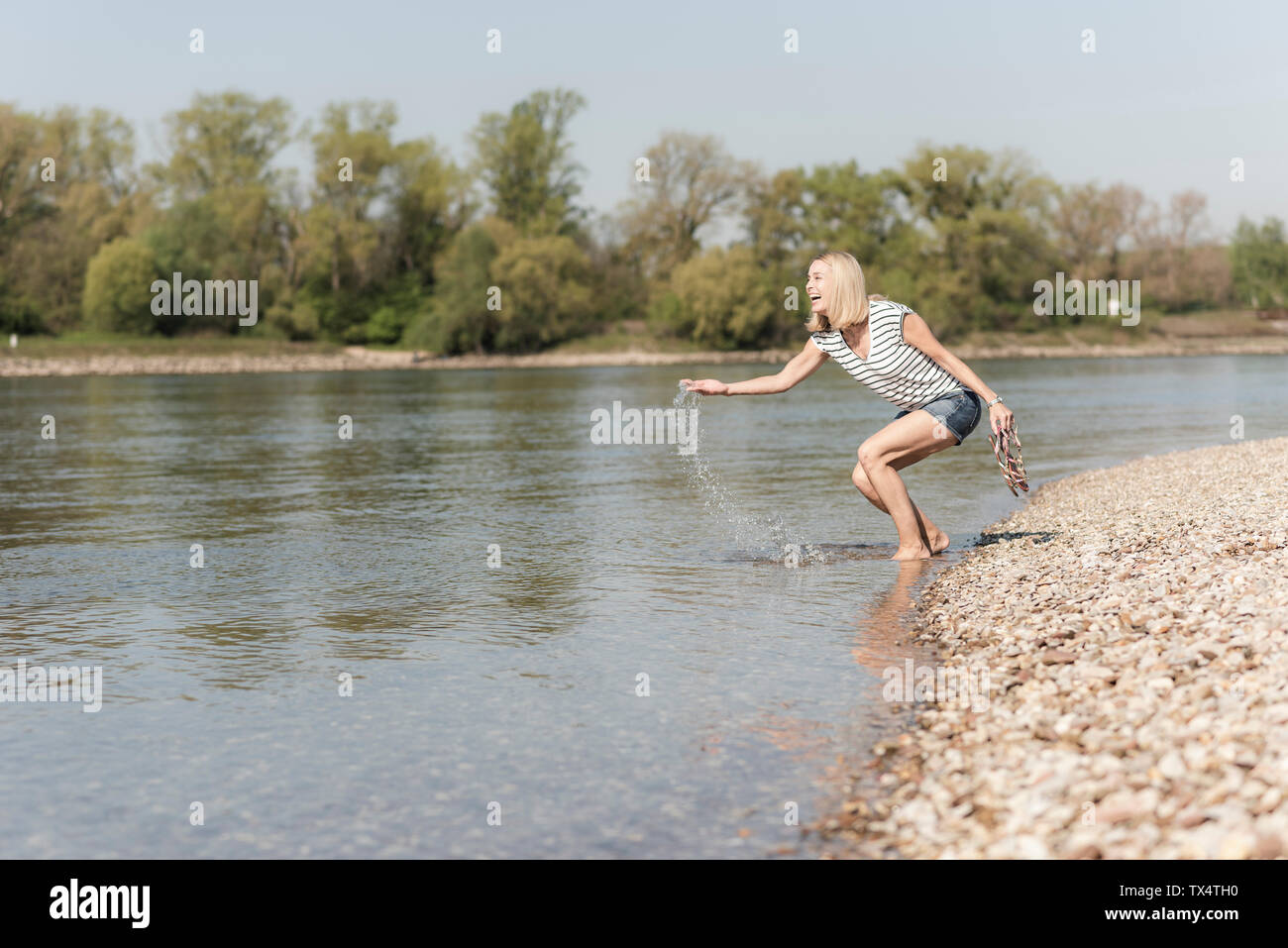 Mature Woman splashing dans une rivière Banque D'Images