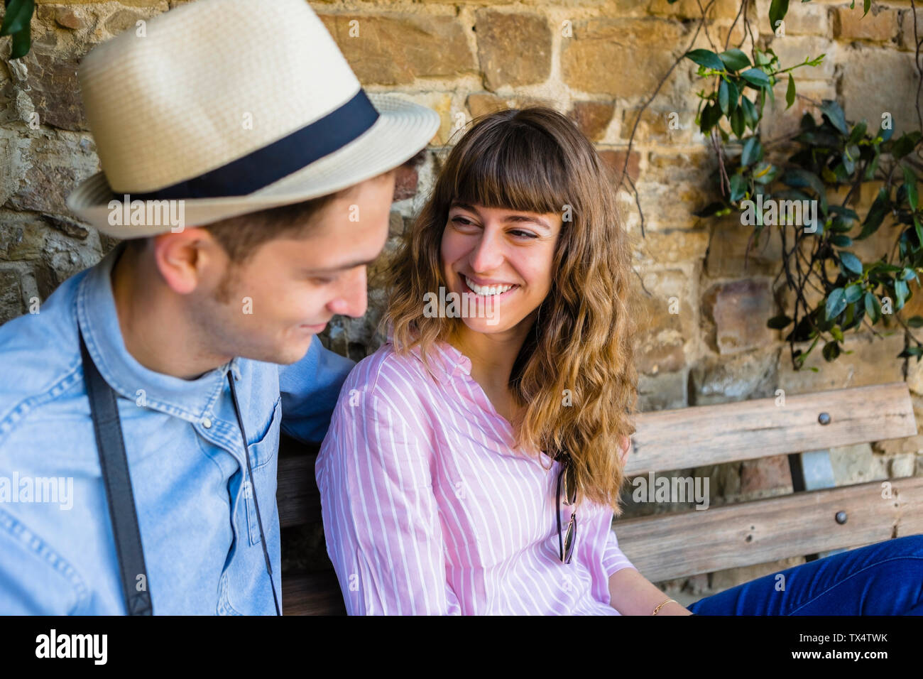 Jeune couple sur un séjour en ville, assis sur un banc, prenant une pause Banque D'Images