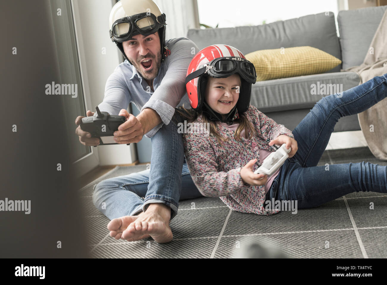 Jeune homme et petite fille portant des casques de motards, jouer au jeu de course avec une console de jeux Banque D'Images