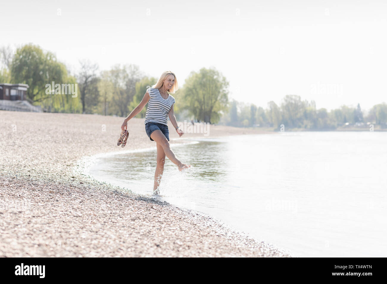 Carefree woman splashing in a river Banque D'Images