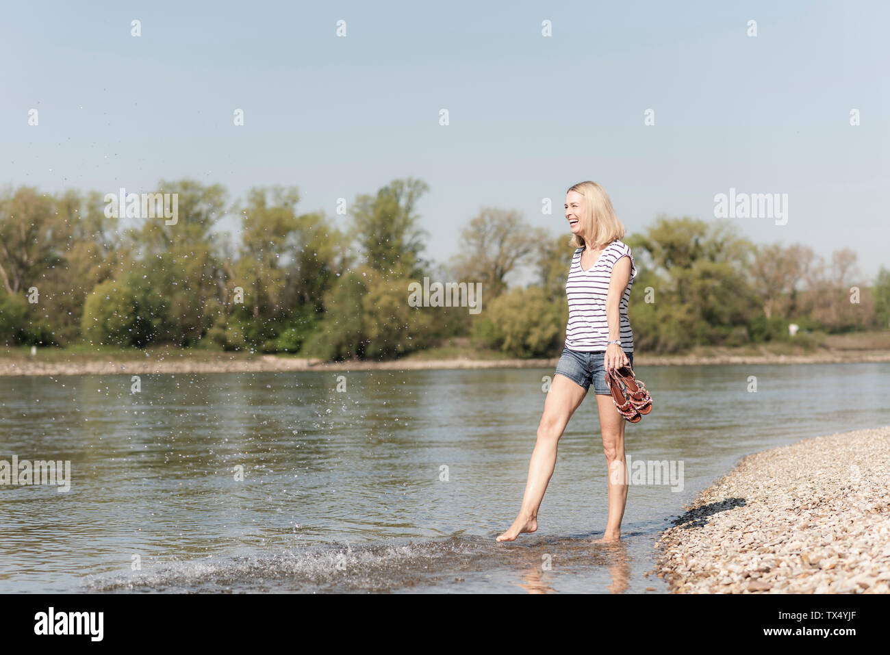 Carefree woman splashing in a river Banque D'Images