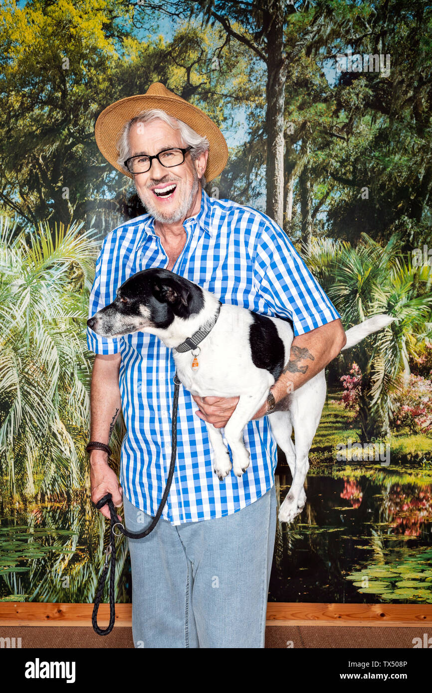 Man avec un chapeau et un chien, debout en face de papier peint photo Banque D'Images