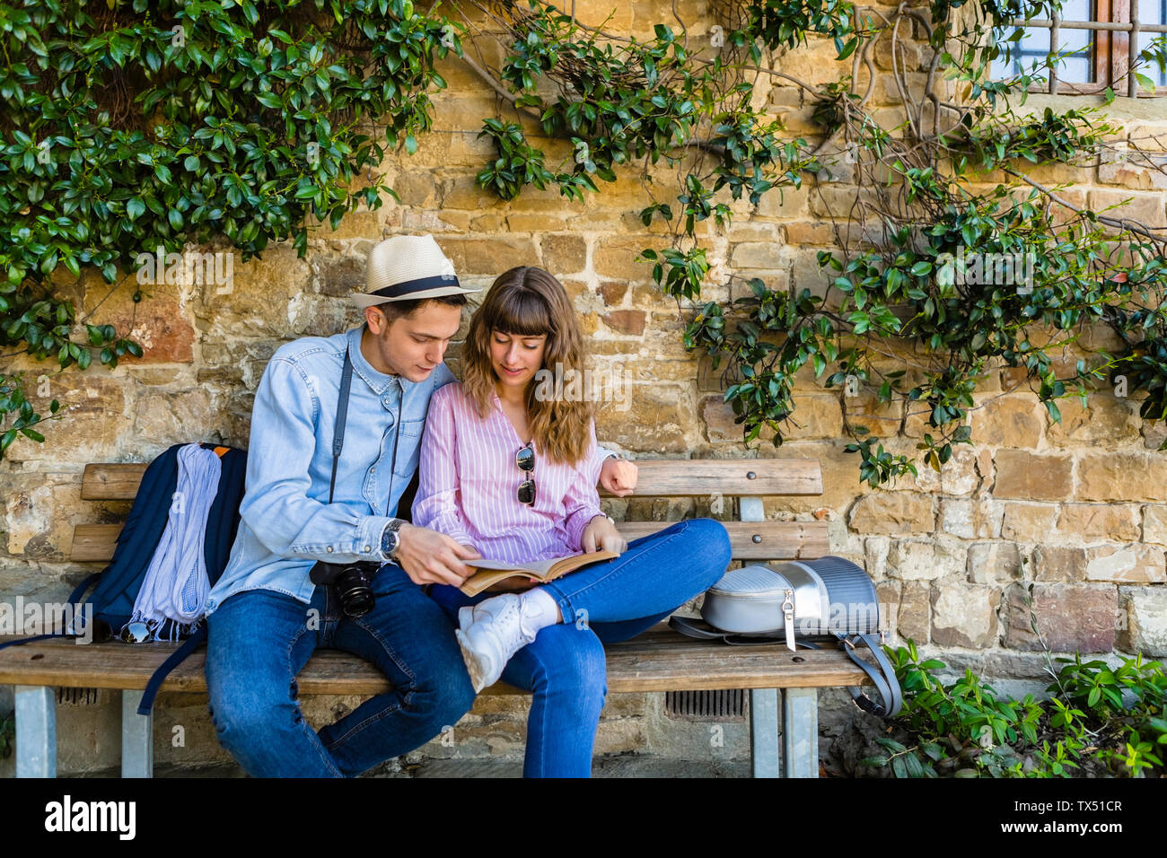 Jeune couple sur un séjour en ville, assis sur un banc, guide de lecture Banque D'Images