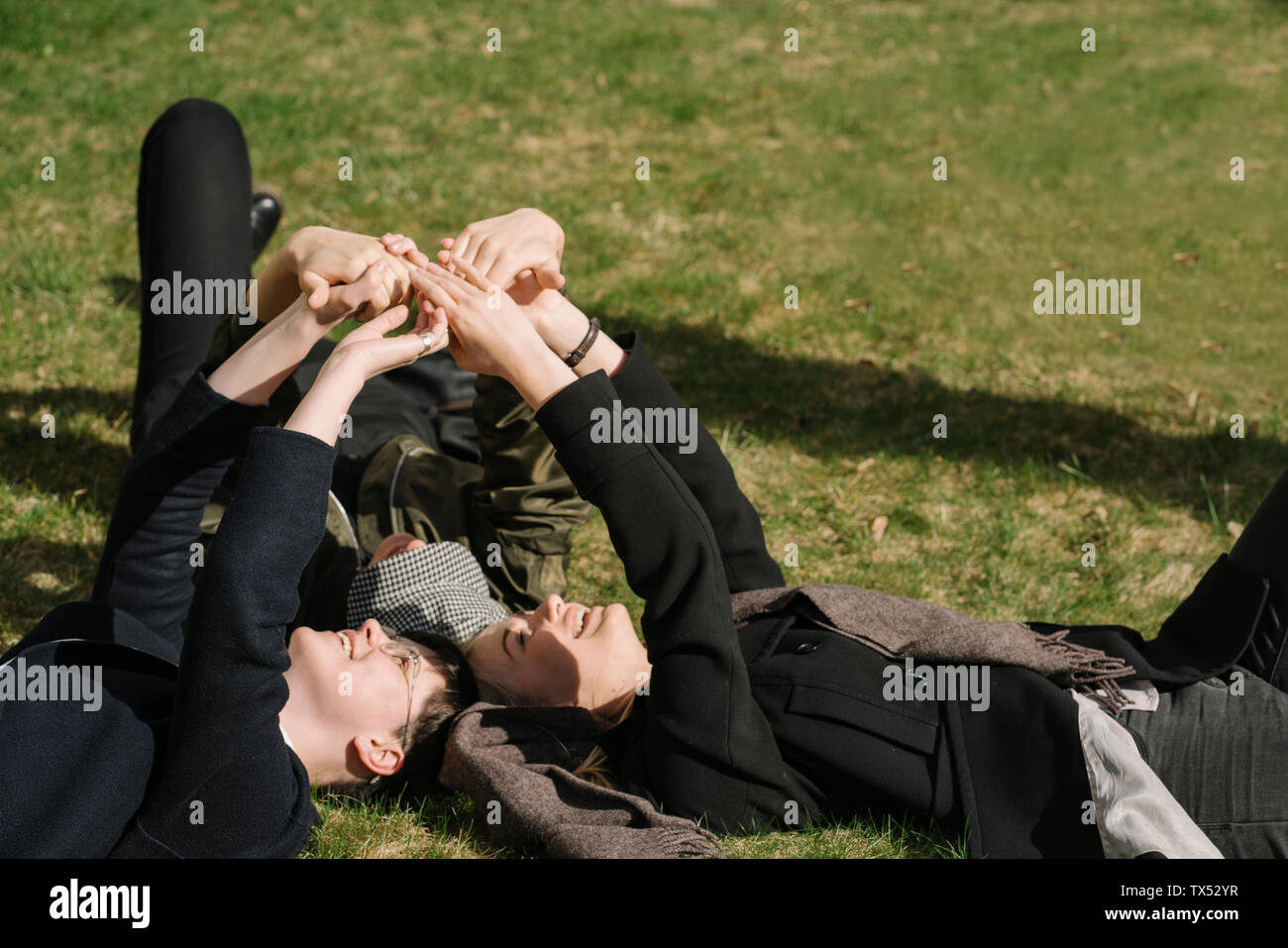 Groupe de jeunes femmes lying in grass mettant leurs mains ensemble Banque D'Images