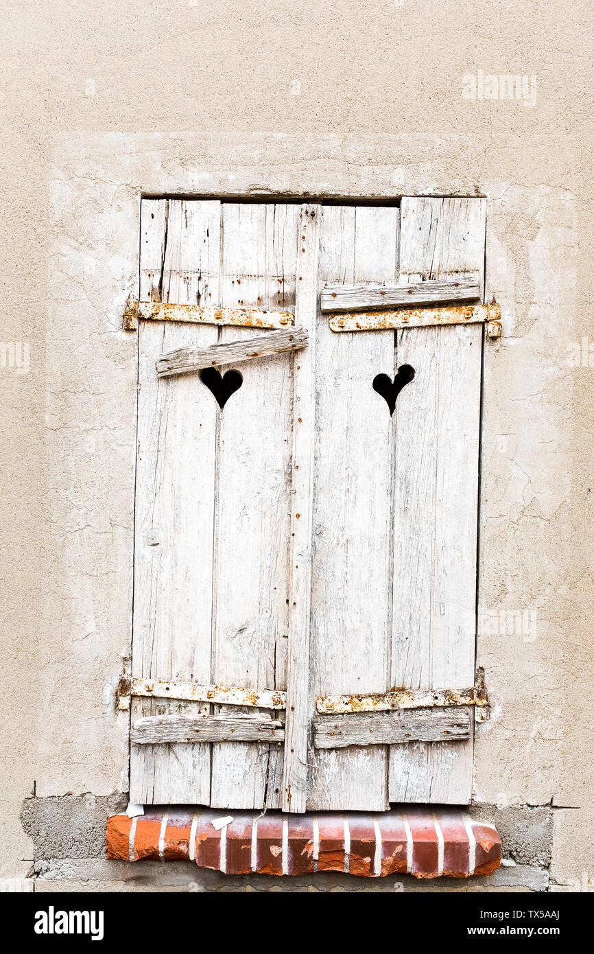 Old weathered volets gris en forme de cœur avec windows dans les trous de mur antique Banque D'Images