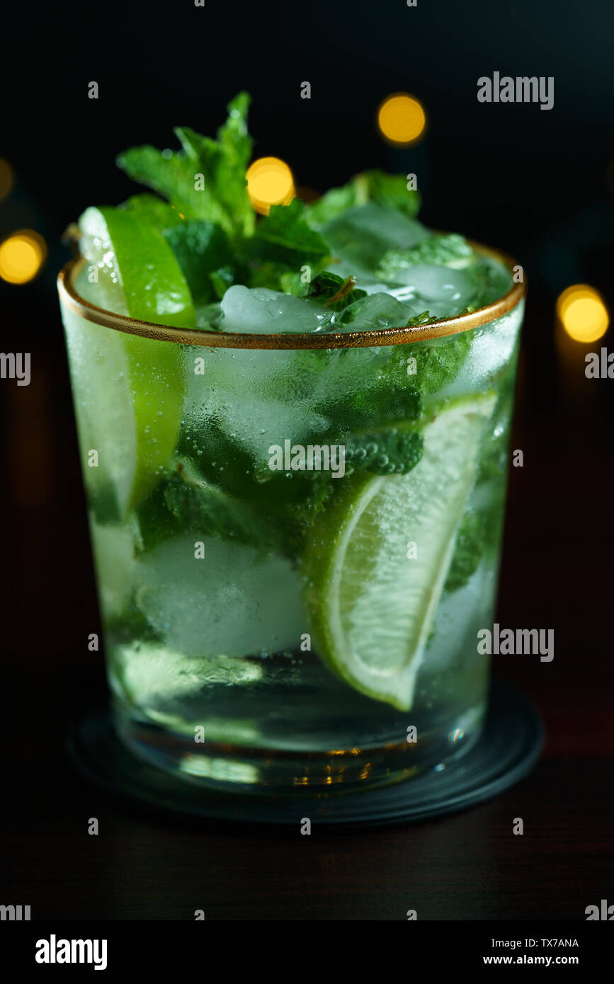 Plan Macro sur le mojito servi dans un verre avec de l'or jante. Table en bois sombre, lumières de fête, haute résolution Banque D'Images