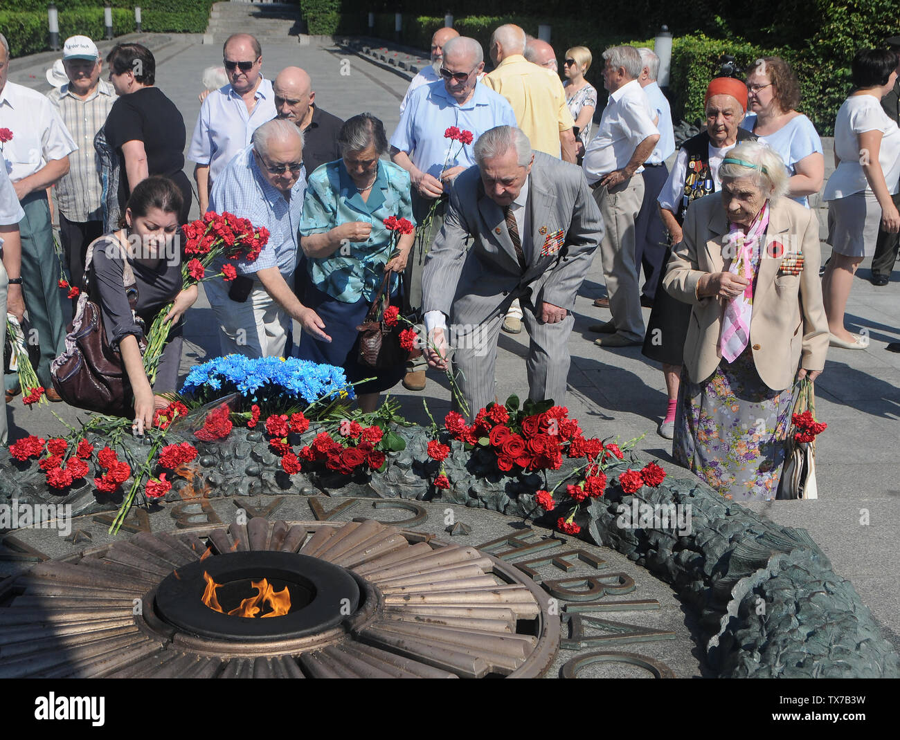 Poser les participants à roses la flamme éternelle au cours d'une cérémonie de dépôt de gerbes sur la Tombe du Soldat inconnu le Jour de deuil et de commémoration des victimes de la guerre à Kiev. Banque D'Images