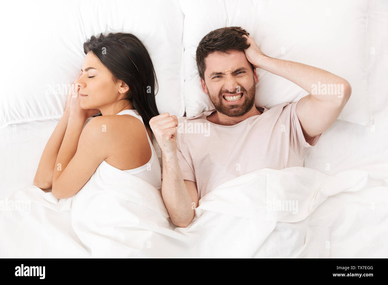 Image d'un jeune homme mécontent se trouve dans lit sous couverture près de  femme endormie Photo Stock - Alamy
