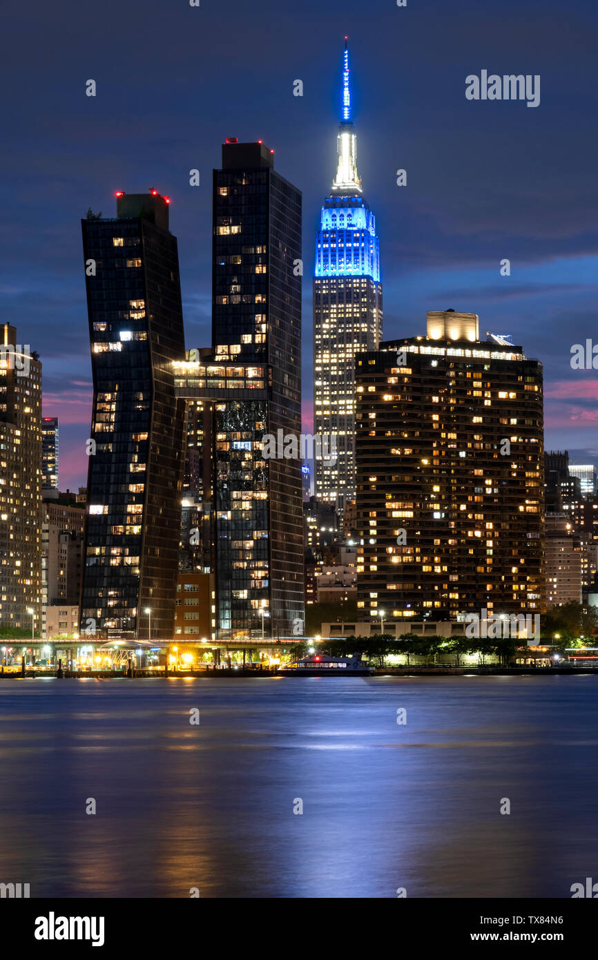 Manhatttan Skyline at night avec le cuivre américain Bâtiments et Empire State Building à travers l'East River, New York, USA Banque D'Images